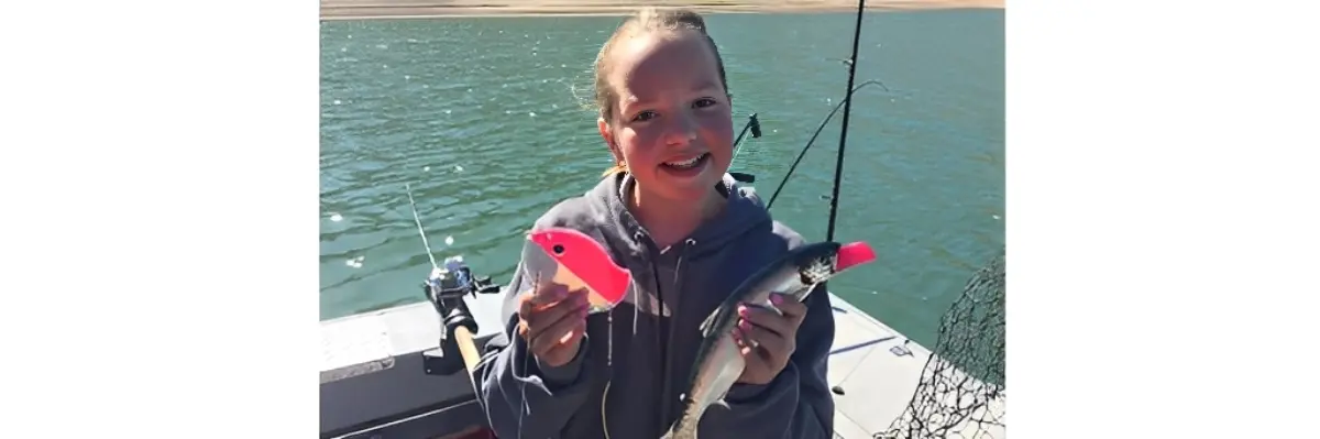 Person holding fish and lure on boat.