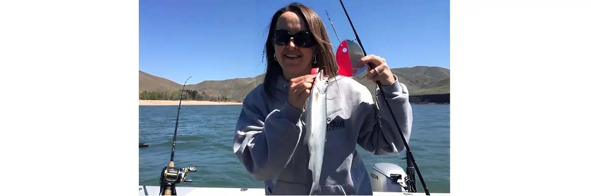 Person holding fish on a boat.