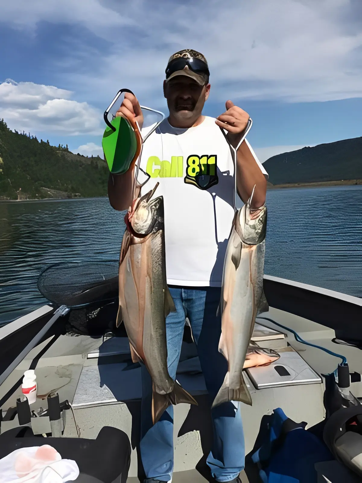 Man holding two large fish on boat.