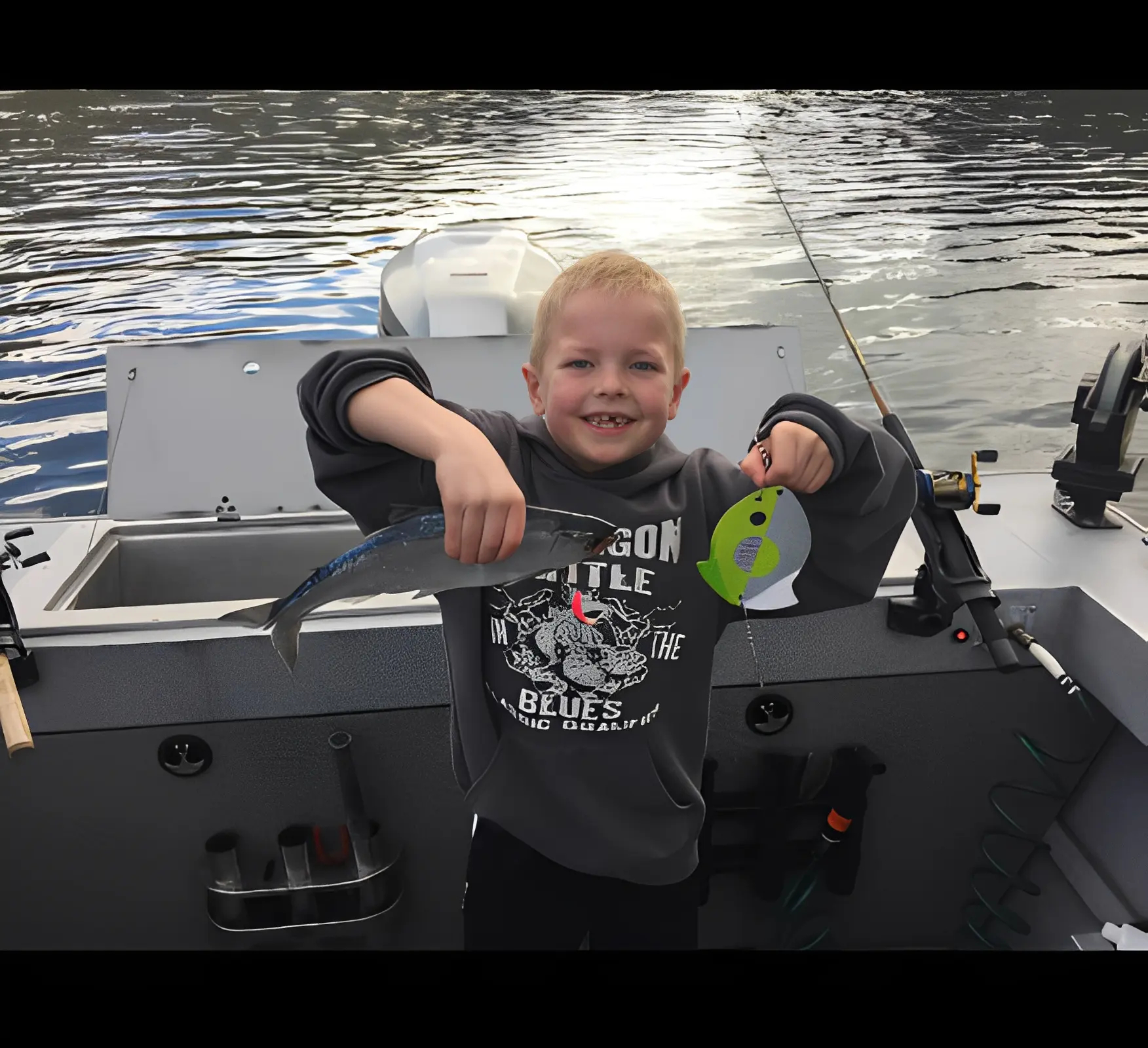 Child proudly holding a fish on boat.