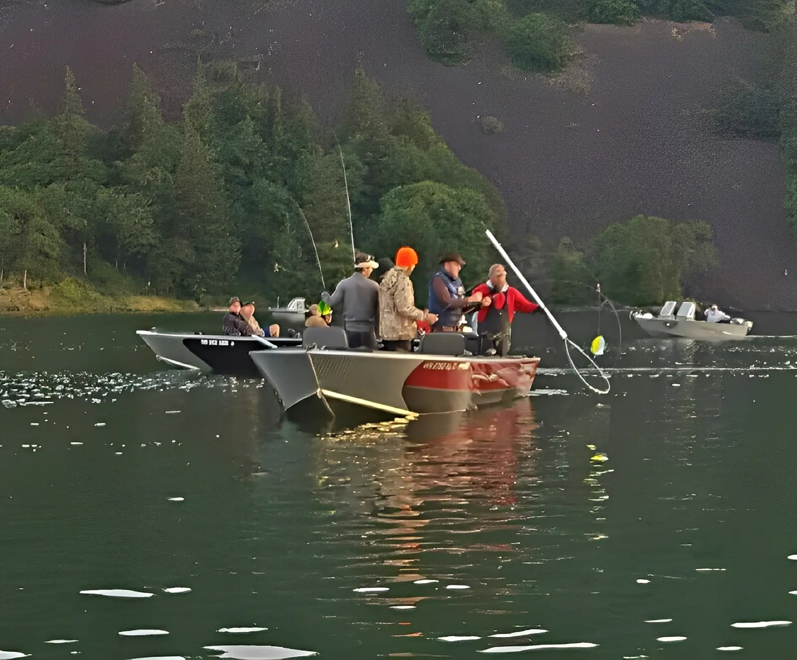 Boats with people fishing on a lake.