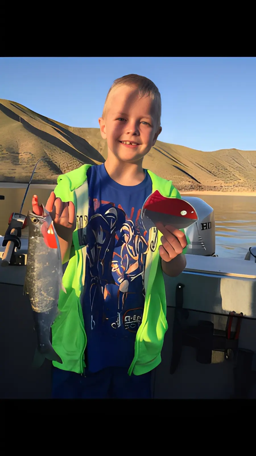 Child smiling while holding a fish caught.