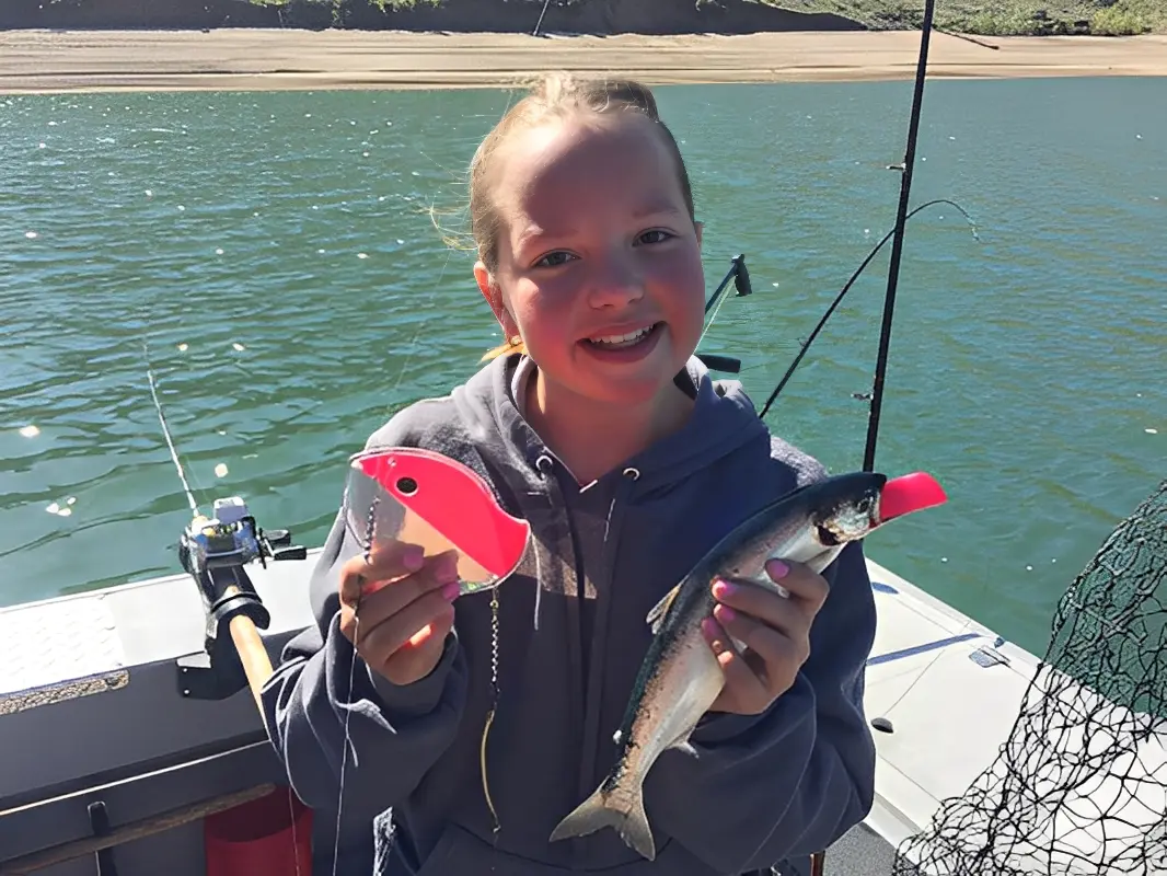 Child holding fish and lure on boat.