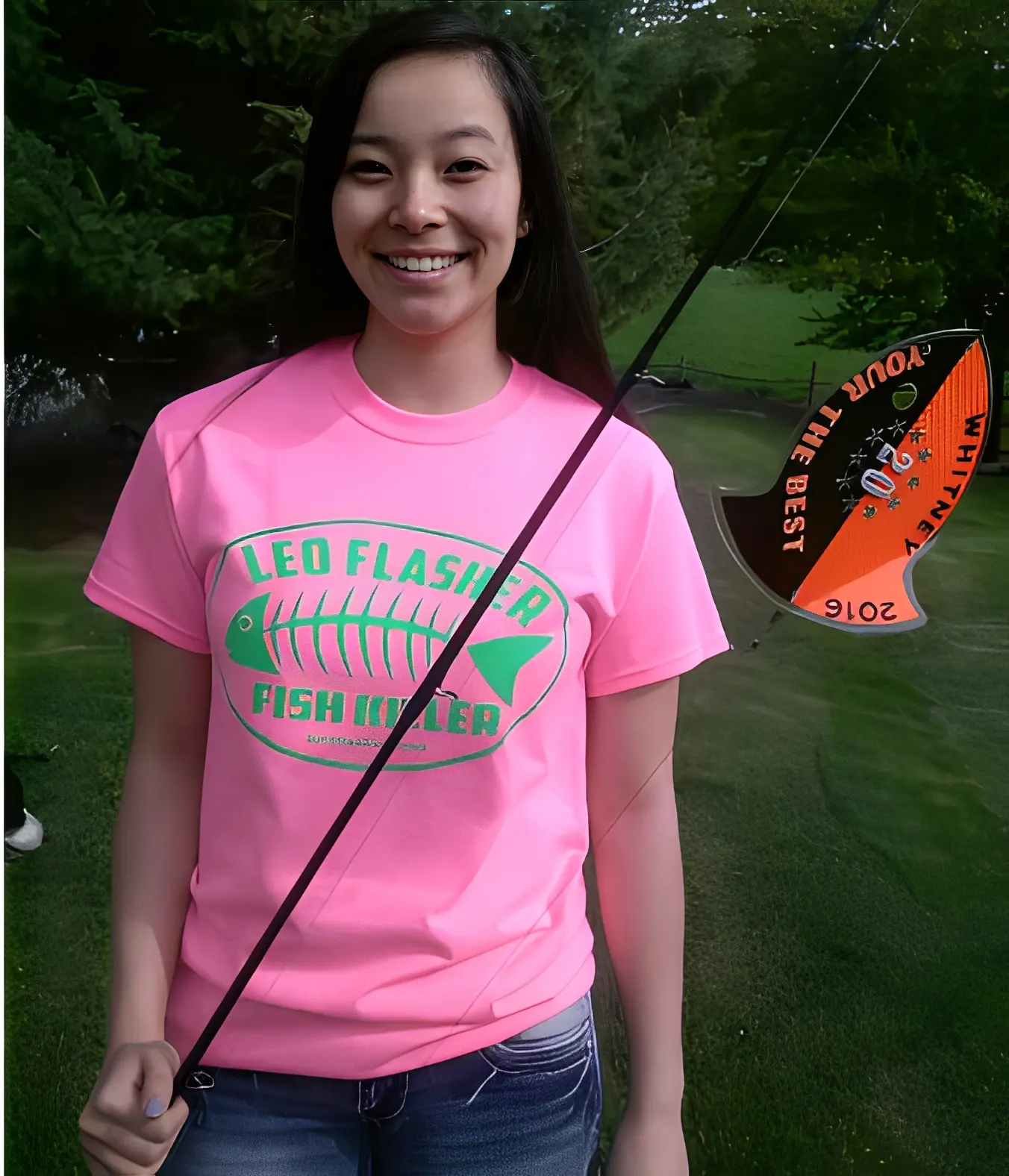 Smiling person holding fishing rod outdoors.