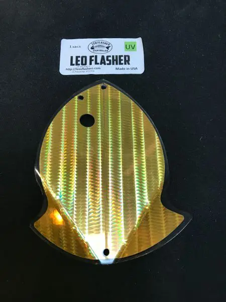 Gold-colored fish-shaped LED flasher cover with two holes.