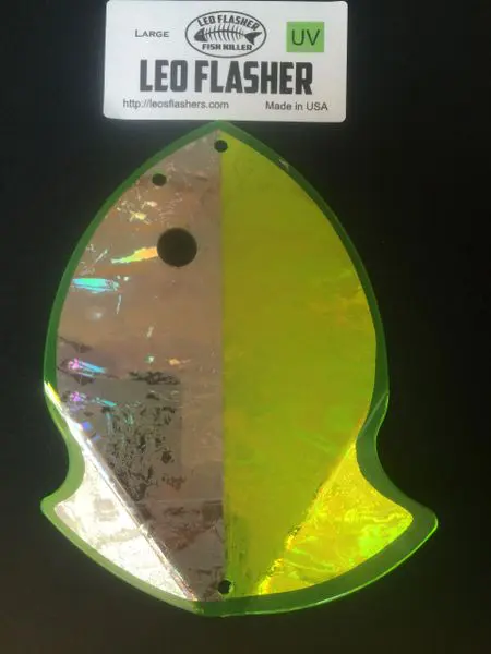 A glowing, greenish-yellow abstract leaf-shaped sign with reflective surfaces.