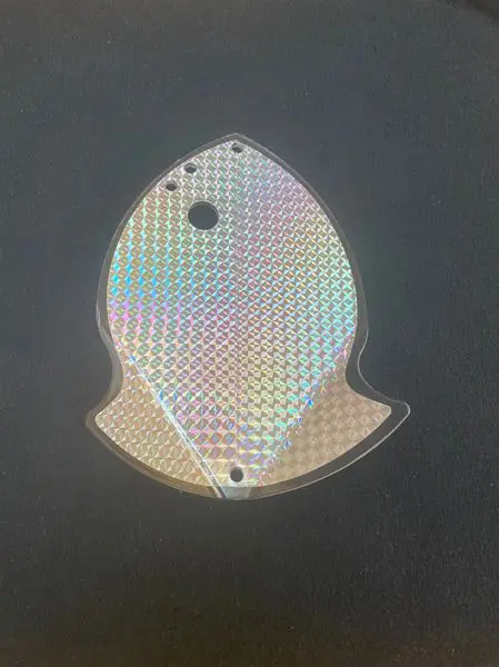 Reflective fish-shaped metal plate with mounting holes.