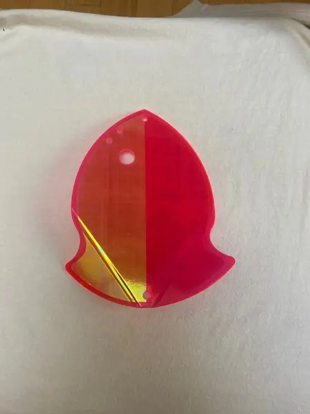 A small, red, bird-shaped translucent object on a white surface.