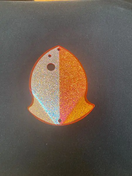 A stylized, shiny orange and white fish-shaped object on a dark background.