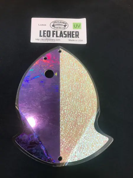 A shiny ghost-shaped LED flasher light with one side purple and the other gold.